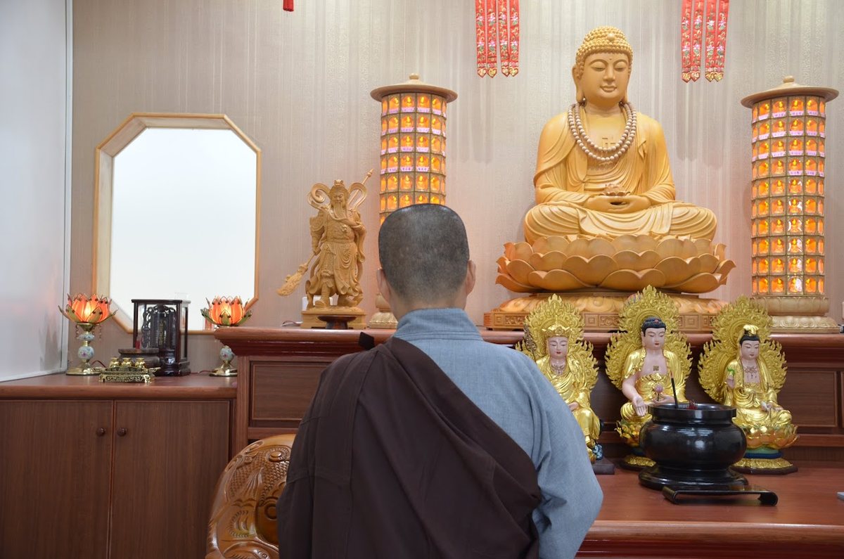 A nun in quiet devotion before the golden Buddha in the main hall